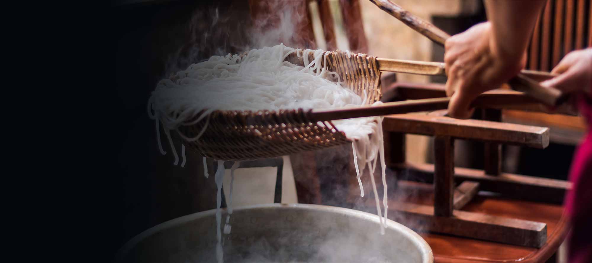 Reisnudeln in einem traditionellen Flechtgefäß kochen